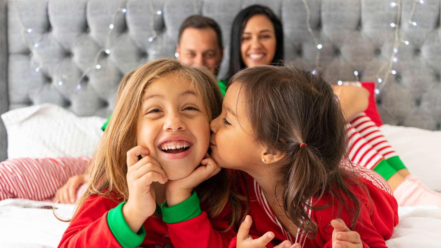 Kids in Christmas pajamas on parent's bed