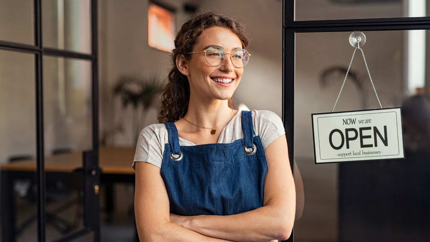 Small business owner female in shop with Open sign