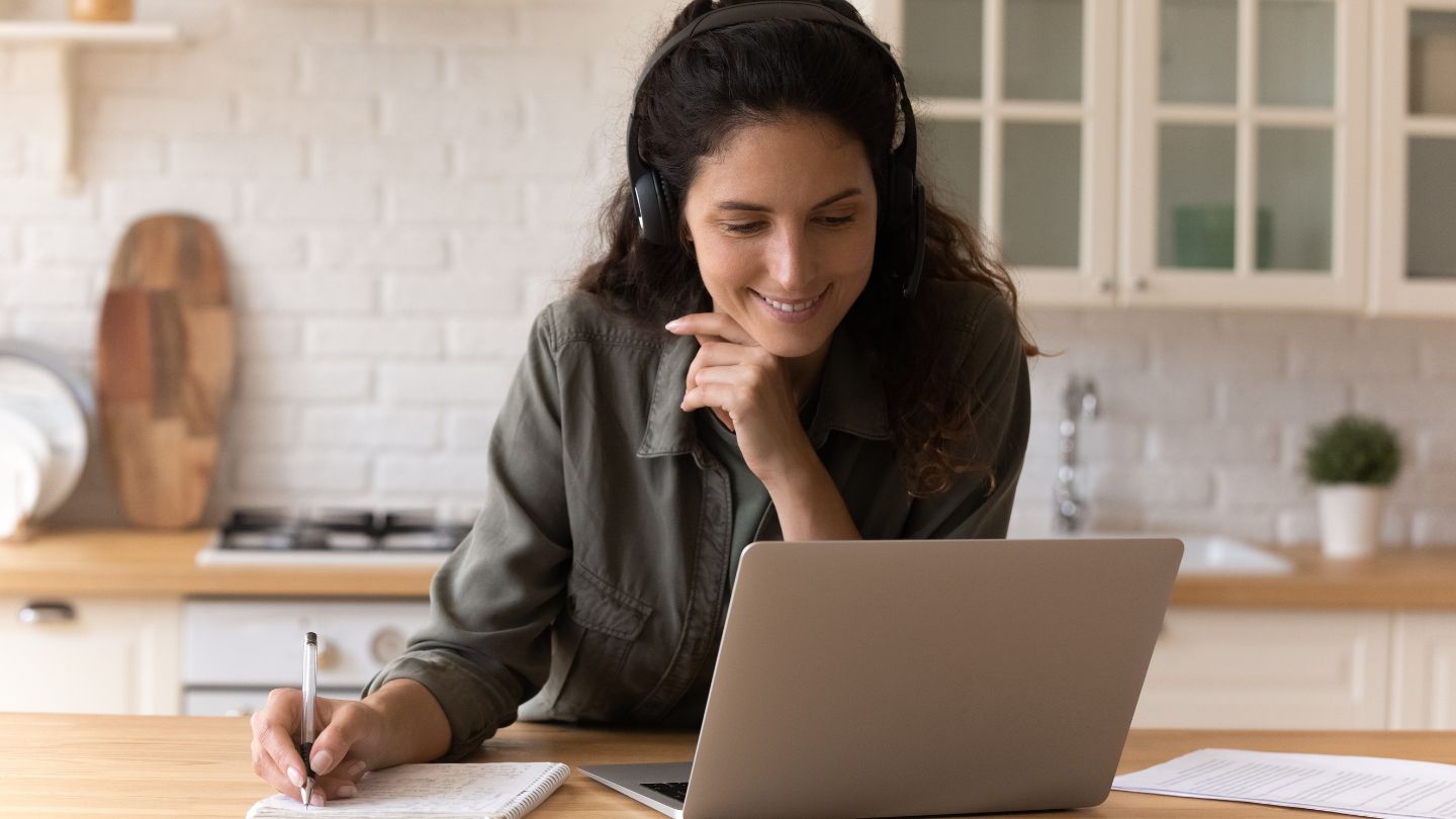 Woman with headphones attending webinar using laptop